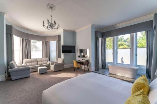 um quarto de hotel com uma cama, uma banheira e um sofá em Oatlands Park Hotel em Weybridge