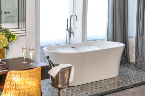 a bath tub in a bathroom with a table and a chair at Oatlands Park Hotel in Weybridge