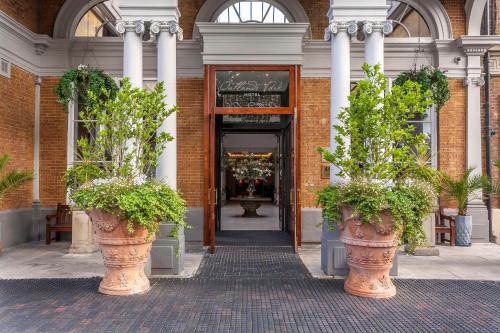 an entrance to a building with two large potted plants at Oatlands Park Hotel in Weybridge