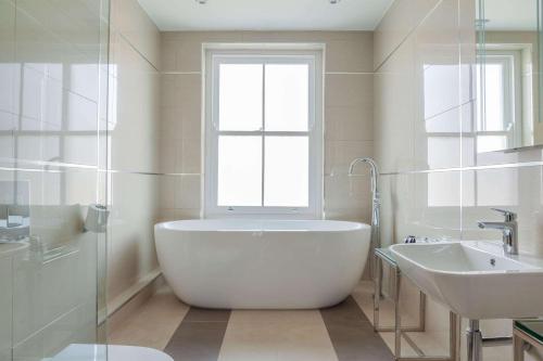 a bathroom with a tub and a sink and a window at Oatlands Park Hotel in Weybridge