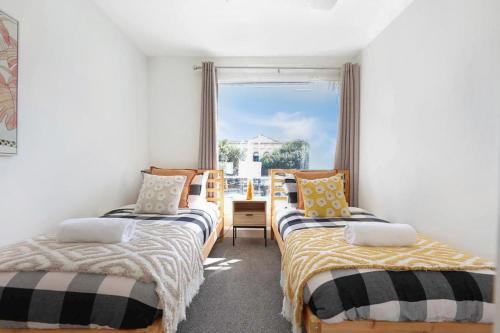 two beds in a room with a window at City Centre Unit Overlooking Ryrie Street! in Geelong