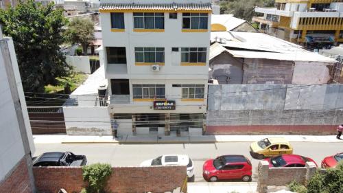 une vue aérienne d'un bâtiment avec des voitures garées sur un parking dans l'établissement Hostal Resident, à Piura