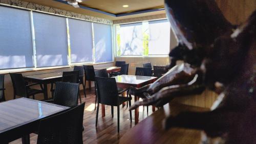 a dining room with tables and chairs and a statue at Isle Inn Guesthouse in Fuvahmulah