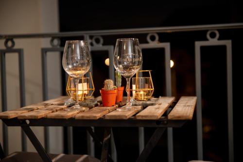 four wine glasses sitting on a wooden table at Hébergement touristique de luxe proche de Paris avec parking gratuit, situé face au parc des expositions et de l'aéroport du Bourget, à 15 min de CDG in Le Blanc-Mesnil