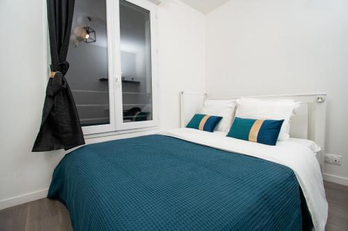 een slaapkamer met een blauw en wit bed en een raam bij Hébergement touristique de luxe proche de Paris avec parking gratuit, situé face au parc des expositions et de l'aéroport du Bourget, à 15 min de CDG in Le Blanc-Mesnil