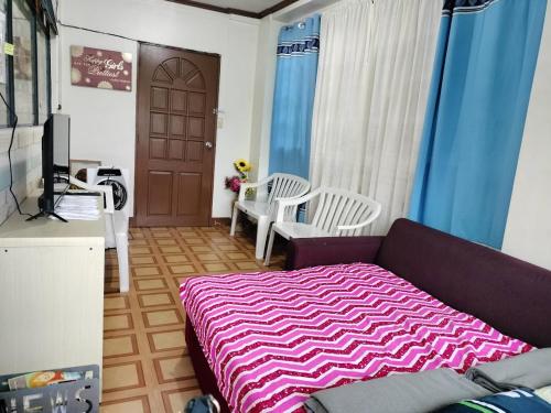 sala de estar con sofá púrpura y 2 sillas blancas en Soc Transient House by GPR en Baguio