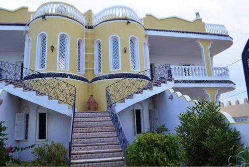 a large yellow and white house with stairs at Laguna in Taguermess