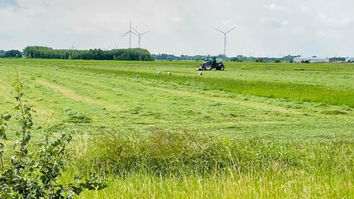 a tractor in a field with wind turbines in the background at Kleine Burg Ovelgönne in Ovelgönne