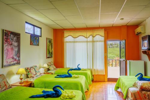 ein Zimmer mit zwei grünen Betten mit blauen Schwänen darauf in der Unterkunft Hospedaje Germania in Puerto Ayora