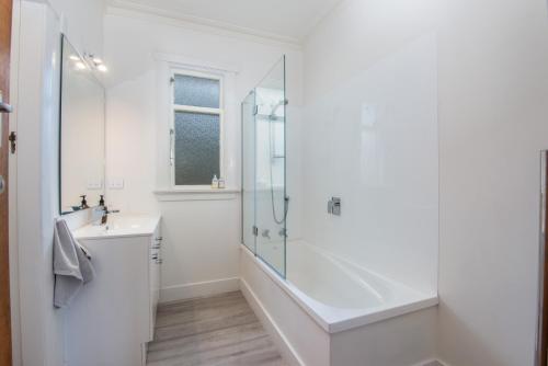a white bathroom with a shower and a sink at Stunning Family Home in Andersons Bay in Dunedin