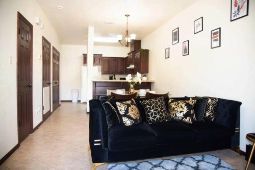 a living room with a black couch and a kitchen at 1 Min to University UTRGV 2BD 2BT town suite in Edinburg