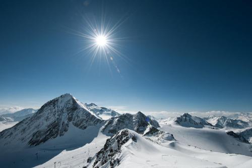 a snow covered mountain with the sun in the sky at Hotel Hoferwirt in Neustift im Stubaital