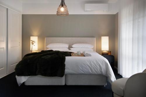 a bedroom with a large bed with white sheets and black blankets at Peahen House in Trentham