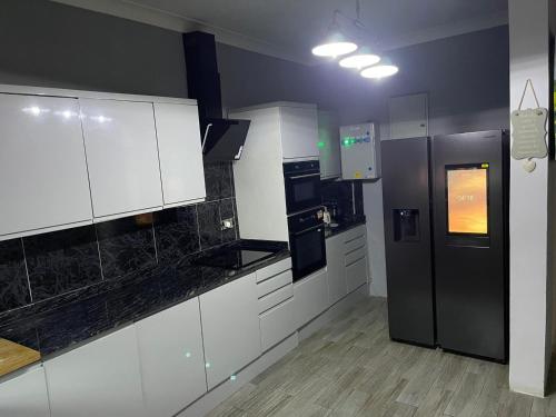 a kitchen with white cabinets and a black refrigerator at Marie & Sons Property in Freetown