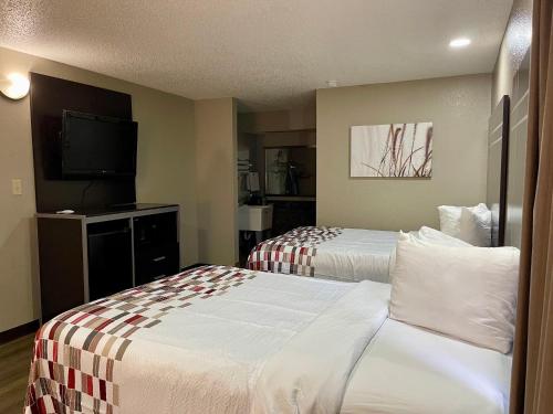 a hotel room with two beds and a flat screen tv at Red Roof Inn & Suites Richland in Richland