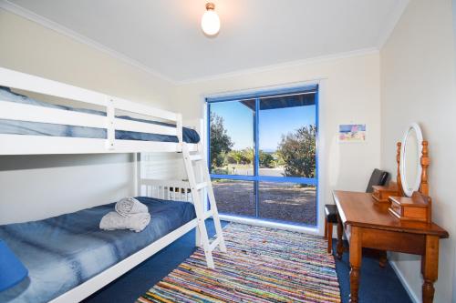 a bedroom with a bunk bed and a desk at Banksia Waters in Lakes Entrance