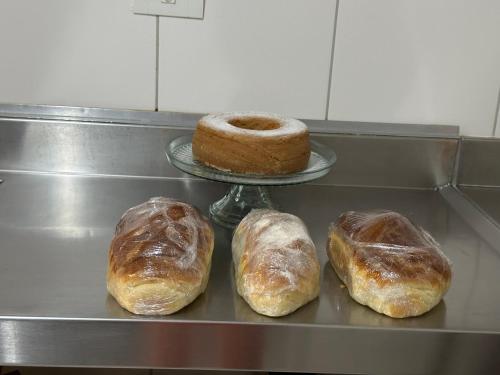 trois pains et un gâteau sur une étagère dans l'établissement POUSADA MINEIRA, à Águas de São Pedro