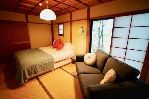 sypialnia z łóżkiem, kanapą, łóżkiem i oknem w obiekcie Sunnsnow Kallin Cottage w mieście Nagano