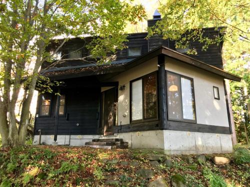 a black and white house with a porch at Sunnsnow Kallin Cottage in Nagano