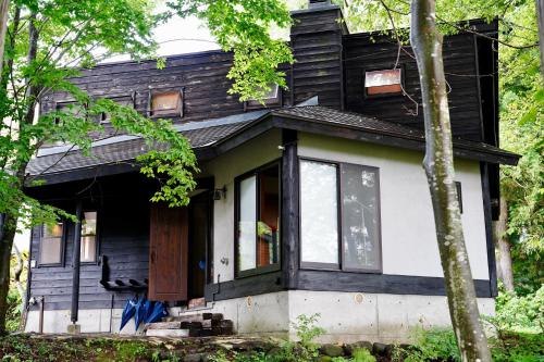 a small black and white house with a door at Sunnsnow Kallin Cottage in Nagano