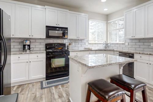 a kitchen with white cabinets and a counter with stools at Around the Bend in Bend