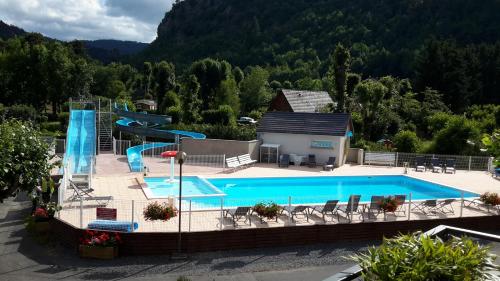 an outdoor swimming pool with a slide and a swimming pool at Camping La Clé des Champs in Saint-Nectaire
