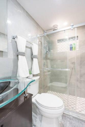 a bathroom with a toilet and a glass shower at New Miami & Calle Ocho Home with Arcade! in Miami