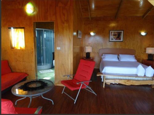 a bedroom with a bed and a red chair at Atavai Hotel Rapa Nui in Hanga Roa