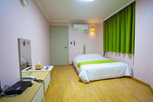a bedroom with a bed and a green curtain at Jeju R Hotel & Guesthouse in Jeju