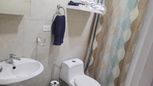 a bathroom with a white toilet and a sink at Acogedor apartamento in San Miguelito