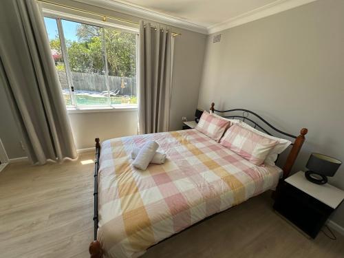 a bedroom with a bed with a plaid blanket and a window at 5 Bedroom 3 bathroom House with Pool, Spa, Voice-Control Smart Home and Game Room in Sydney