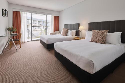 a hotel room with two beds and a balcony at Rydges Resort Hunter Valley in Lovedale