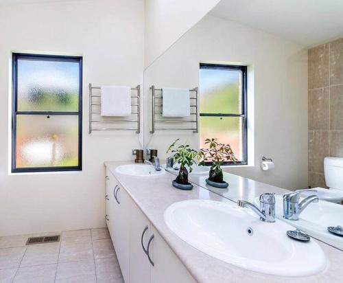 Baño blanco con 2 lavabos y 2 ventanas en Spacious, light-filled retreat, en Warrnambool