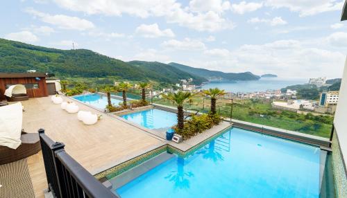 uma varanda com uma piscina e vista para a água em Friemily Pool Villa & Hotel em Geoje