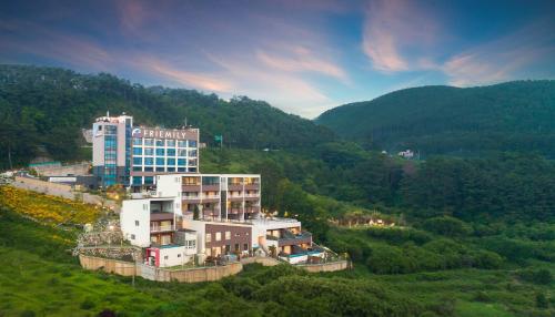 a large building on top of a hill with trees at Friemily Pool Villa & Hotel in Geoje 