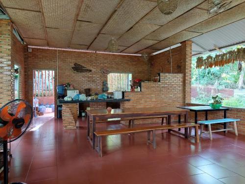 comedor con bancos y pared de ladrillo en The Lazy Farm - Homestay & Glamping, en Mewal
