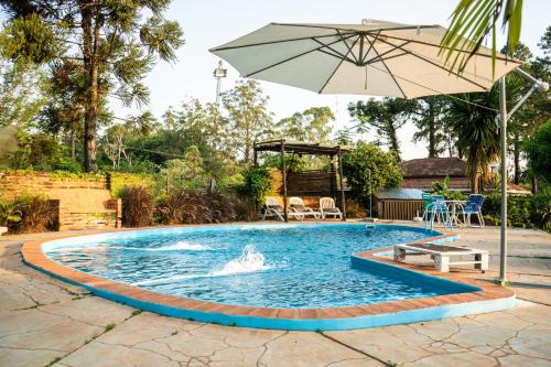 a pool with an umbrella and a table and chairs at " Casa quinta "San Bernardo" Con Pileta y amplio jardín in Posadas
