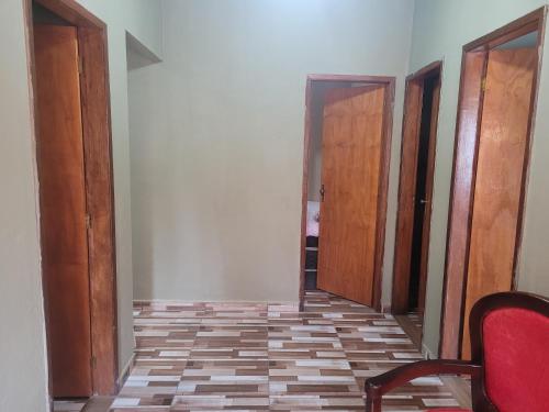 um corredor vazio com duas portas e uma cadeira vermelha em Casa de praia em carne de vaca em Goiana