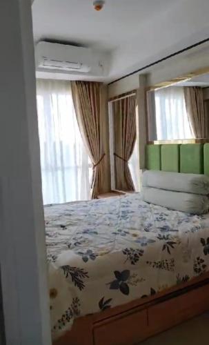 um quarto com uma cama com colcha floral em Apartemen Skylounge Makassar em Manda