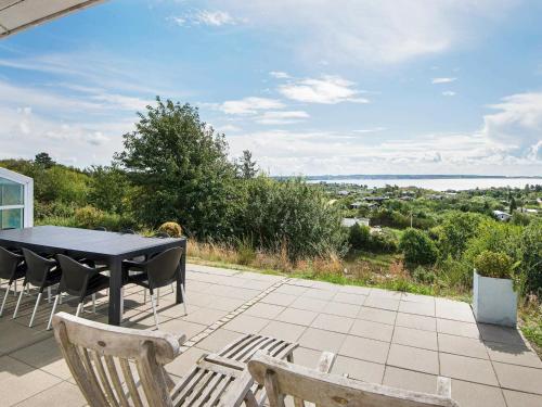 a table and chairs on a patio with a view of the water at 8 person holiday home in Ebeltoft in Ebeltoft