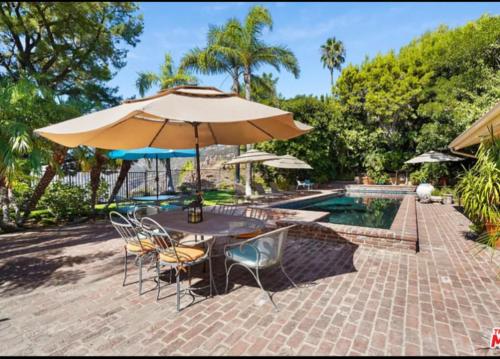 a table and chairs with an umbrella next to a pool at Lux Villa Ocean View Pool &Spa in Malibu