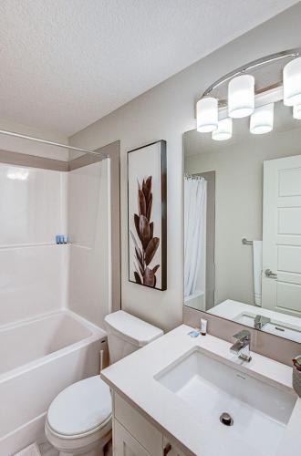 a bathroom with a toilet sink and a mirror at Cozy New Suite in Seton, South Calgary in Calgary