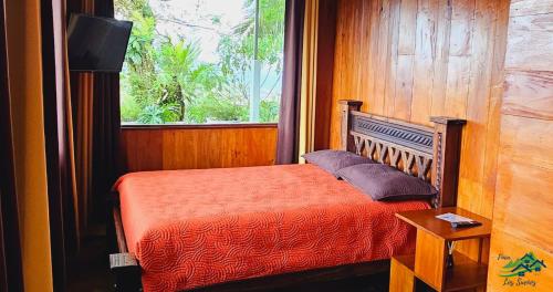 a bedroom with a bed with a window and a television at Cabaña Colibrí in Quesada