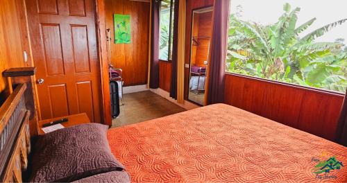 a bedroom with a bed and a large window at Cabaña Colibrí in Quesada