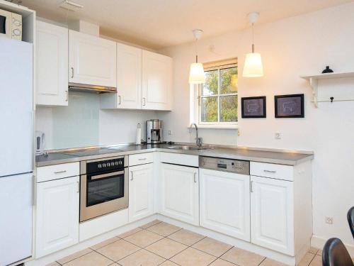 a white kitchen with white cabinets and appliances at Modern holiday home with sauna in Gjern