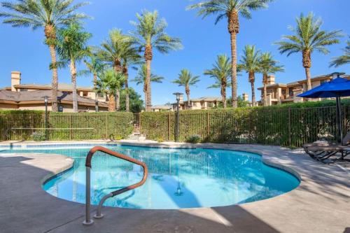 a swimming pool with palm trees and a fence at Scottsdale Links Resort in Scottsdale