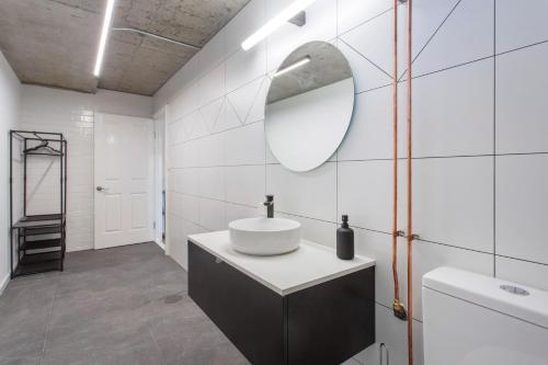 een witte badkamer met een wastafel en een spiegel bij Studio Escape in Hamilton Hill