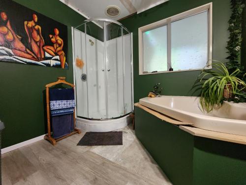 baño verde con bañera y lavamanos en The Treehut, en Island Bay