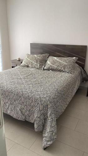 a bed with a black and white comforter and pillows at ayllu in Arica