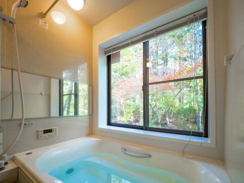 een badkamer met een bad en een raam bij スイートヴィラ NASU四季リゾート in Nasu